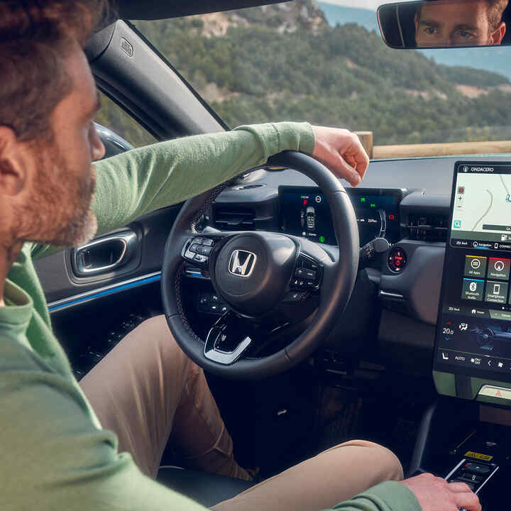 Man som kör en Honda e:Ny1 med navigering på den digitala förardisplayen.