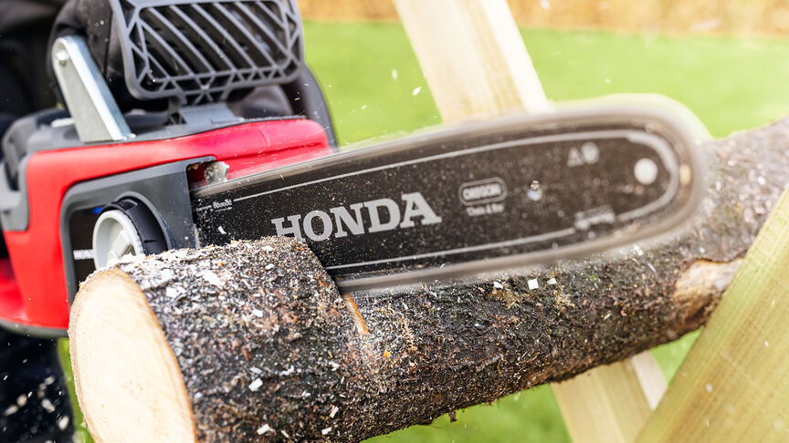 Närbild av en modell som kapar träd med en Honda batteridriven motorsåg.