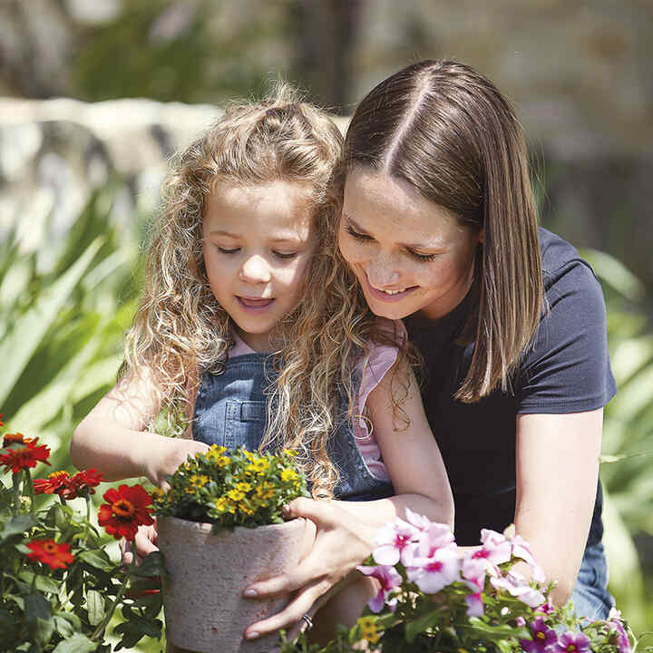 Mor och dotter planterar blommor.