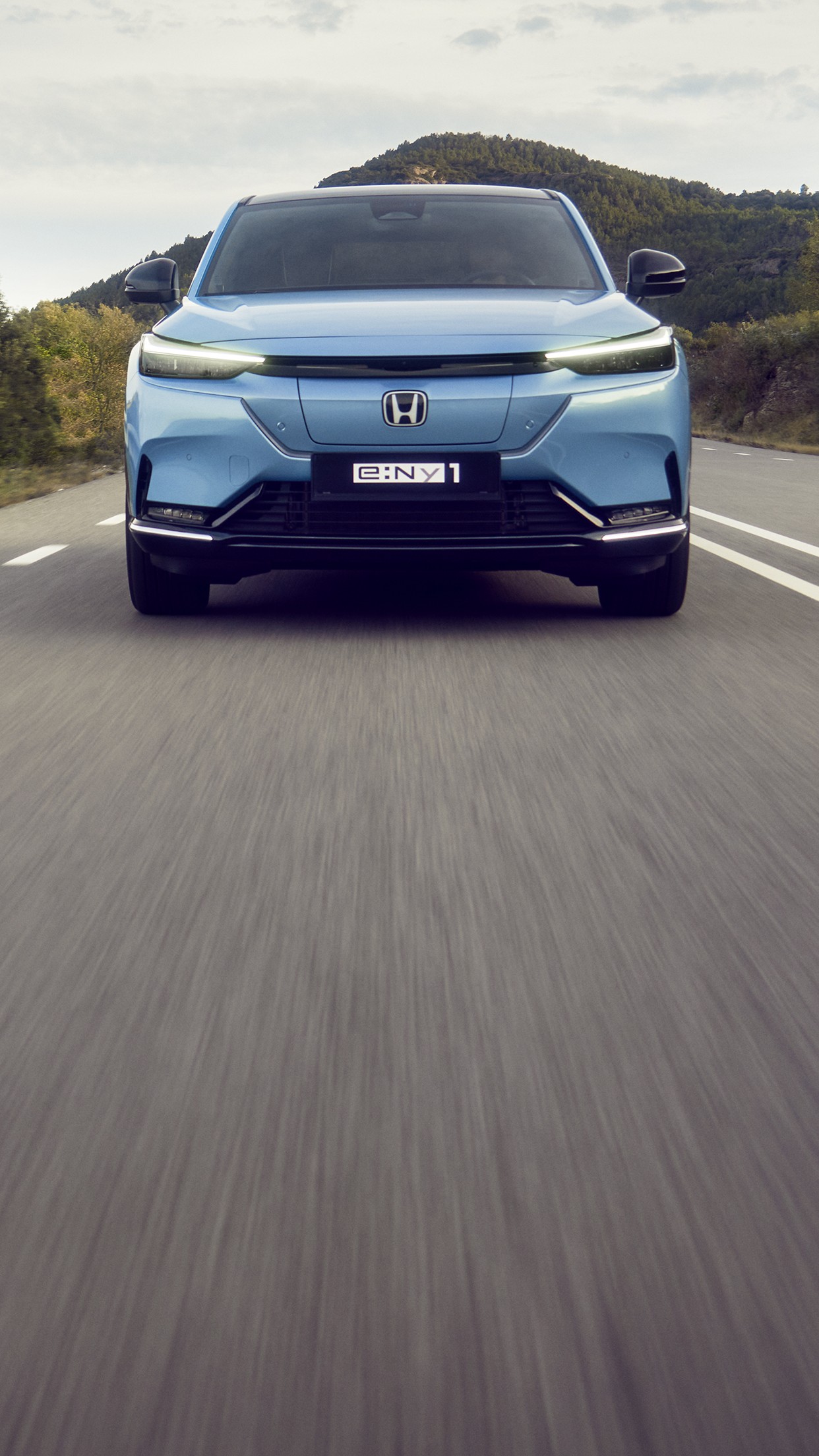 Vy framifrån av en Honda e:Ny1 i ett bergigt område. 