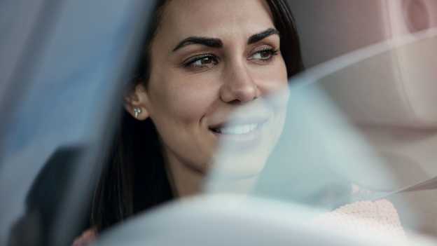 Närbild på kvinna som tittar ut ur ett öppet bilfönster