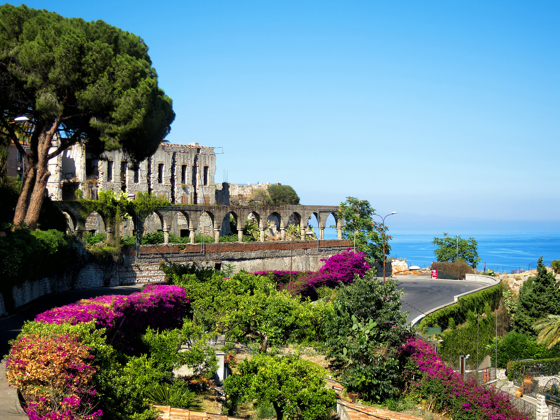 En färgglad trädgård nära en gammal byggnad på Sicilien, Italien