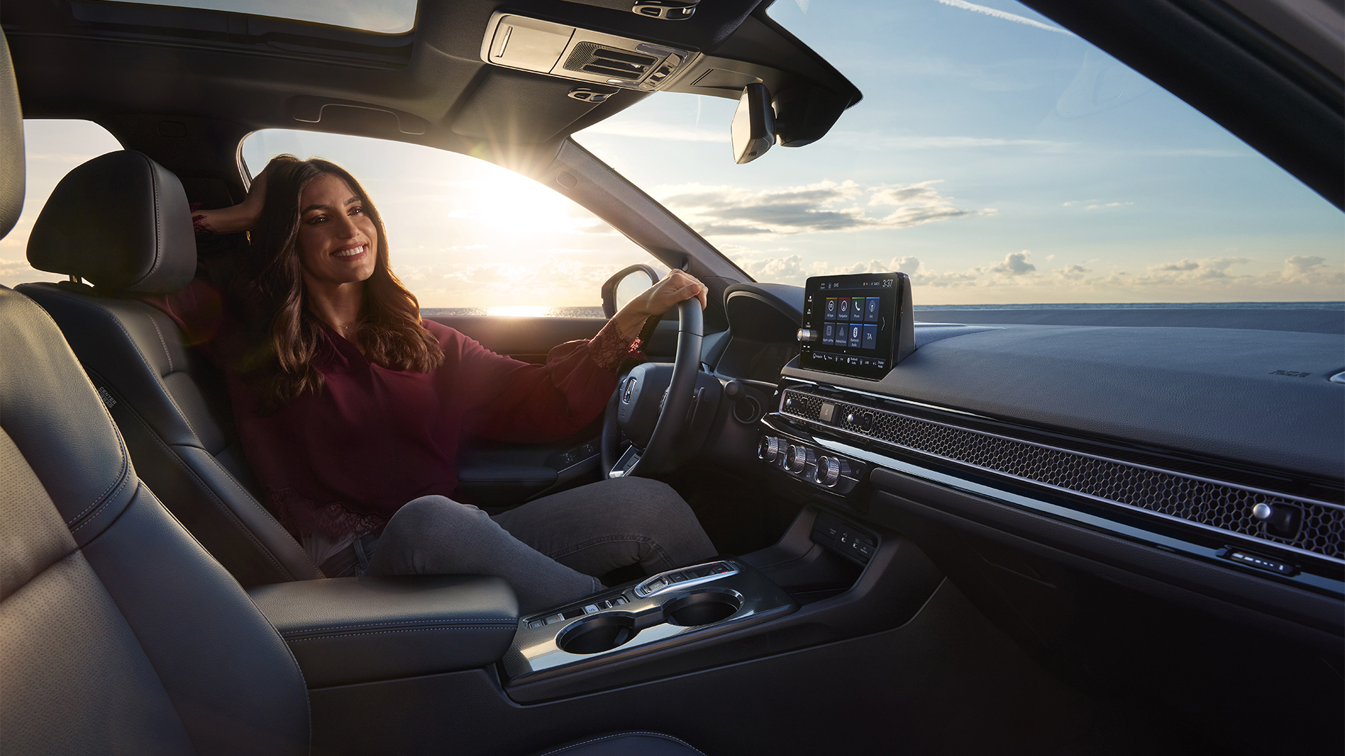 Photo shot from the interior of Civic Hybrid, a woman sitting in the car, next to the sea.