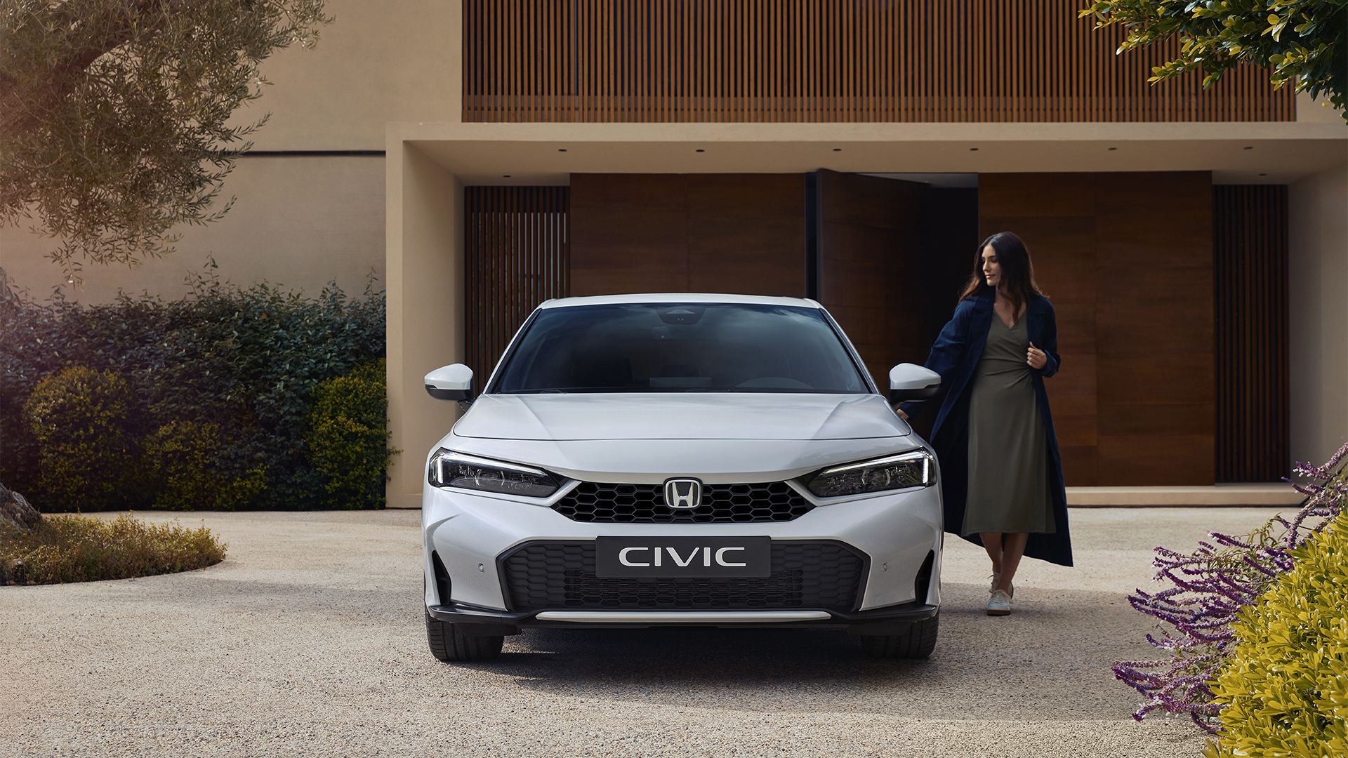 Front shot of a Civic Hybrid, with a woman opening its door.