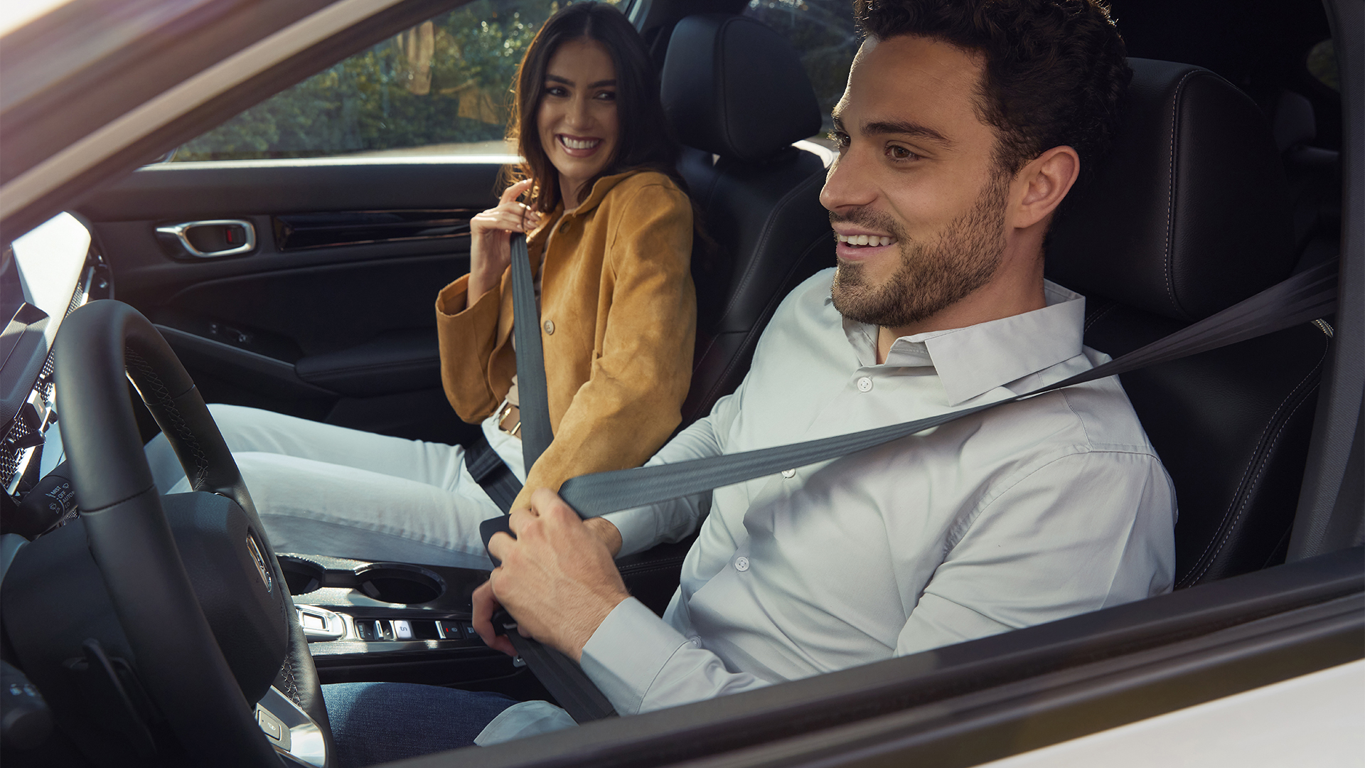 Två personer spänner fast sina bilbälten i Honda Civic Hybrid.