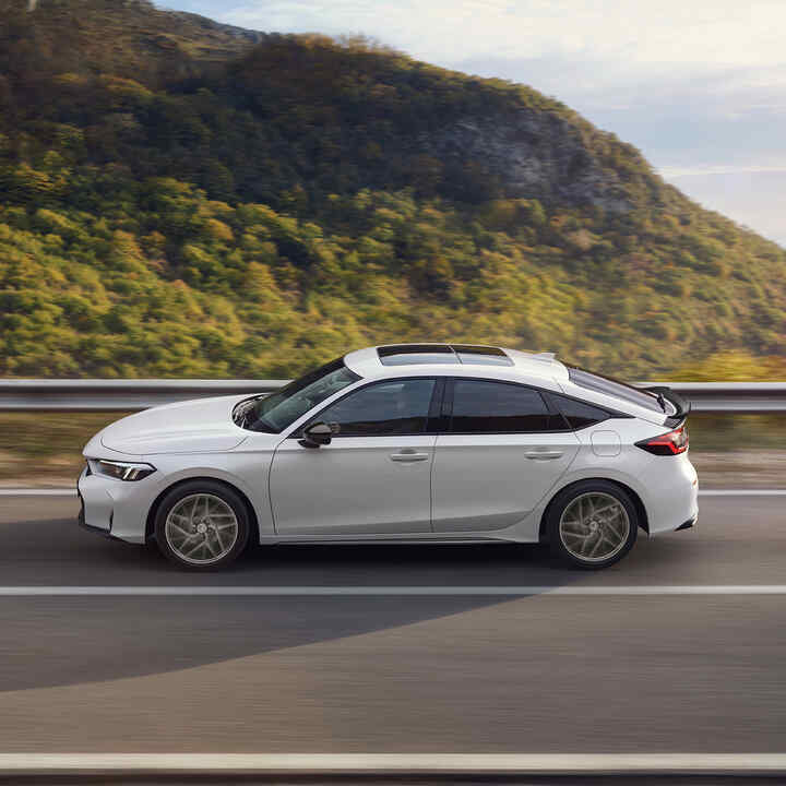 Honda Civic Hybrid i rörelse på en motorväg, med naturskön utsikt.