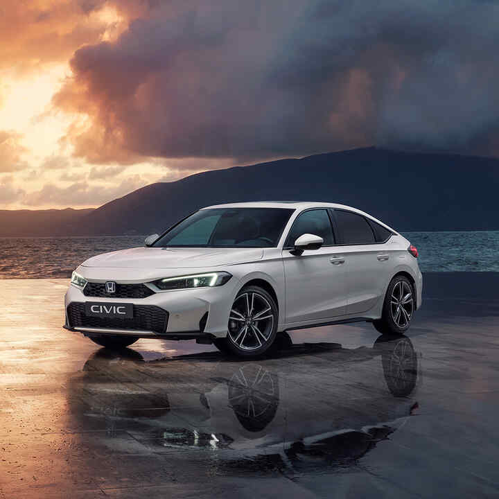 Civic Hybrid parkerad bredvid ett hav i solnedgången.