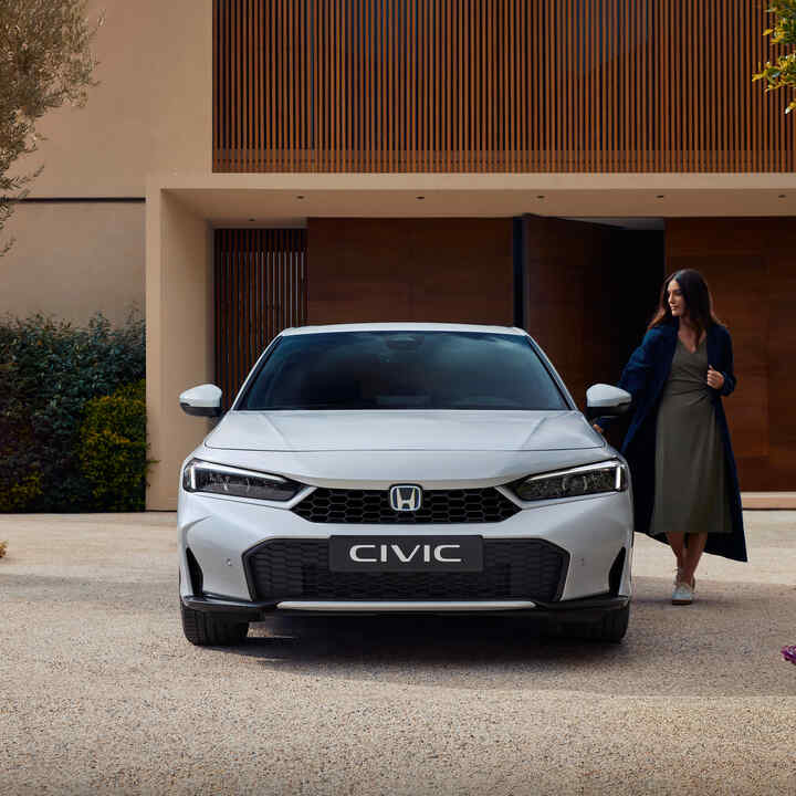 Frontalbild av en Civic Hybrid, med en kvinna som öppnar sin dörr.