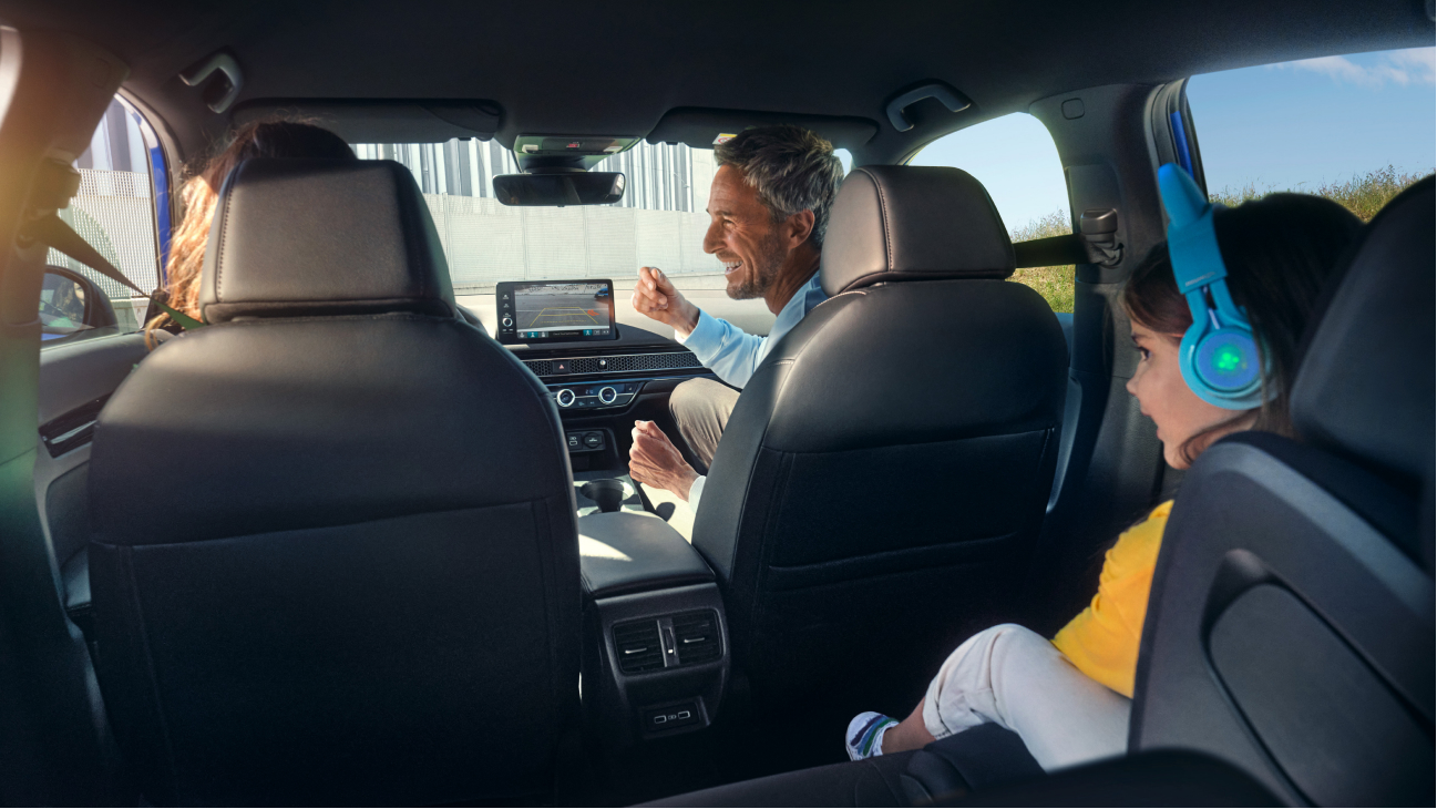 Utsikt från baksätena mot en familj som sitter inne i bilen. 