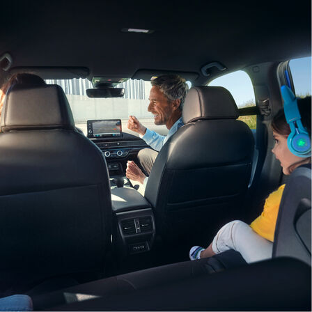 Utsikt från baksätena mot en familj som sitter inne i bilen.