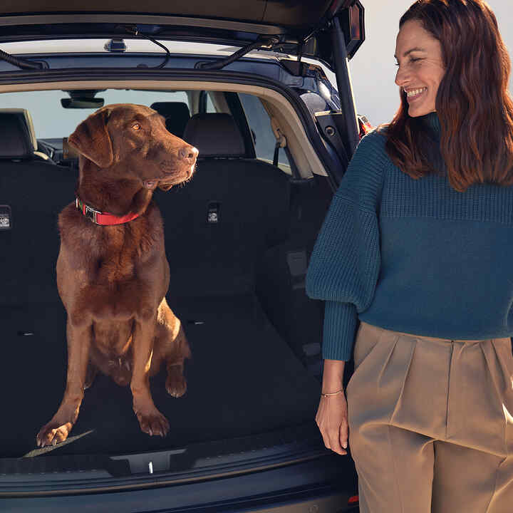 Bakåtvänd Honda CR-V Hybrid med hund och modell som sitter inne i bagageutrymmet.