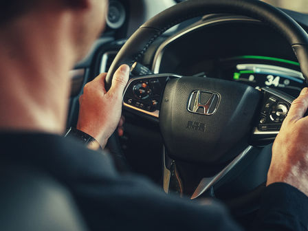 Närbild av modell med ratten i Honda CR-V Hybrid.