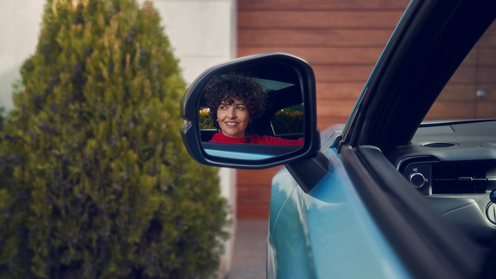 Kvinnors reflektion i dörrbackspegeln på Honda e:Ny1.