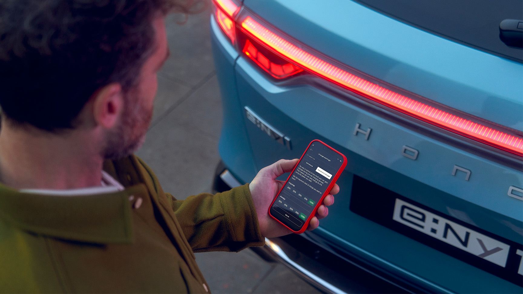 Man som tittar på My Honda Plus-appen bredvid Honda e:Ny1