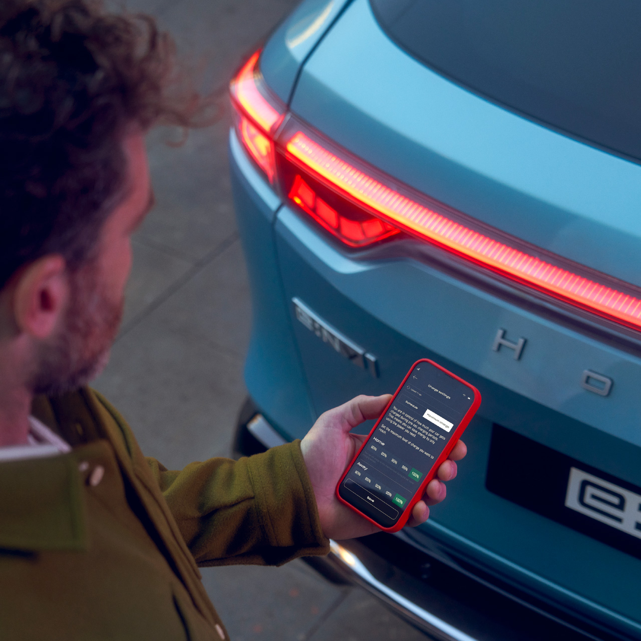 Man som tittar på My Honda Plus-appen bredvid Honda e:Ny1