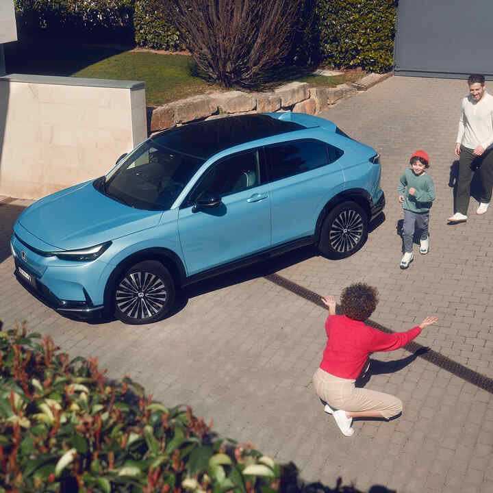 Vy snett framifrån av Honda e:Ny1 Prototyp parkerad utanför en byggnad.