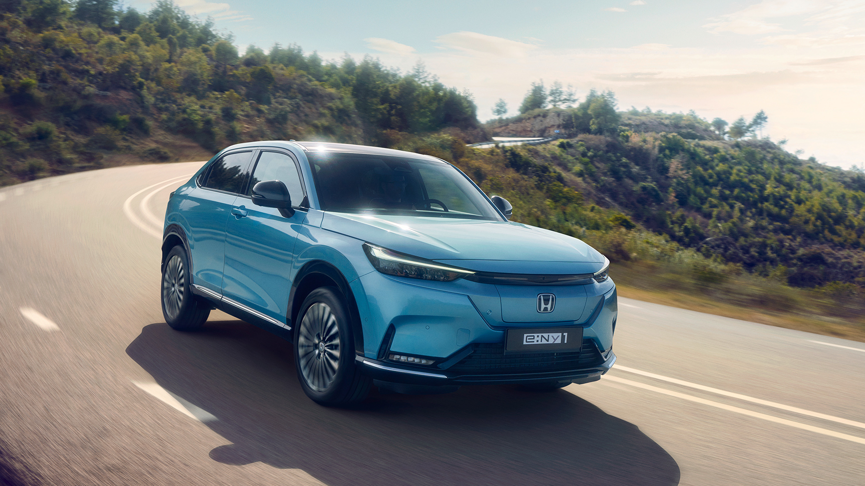 Trekvarts vy framifrån av en Honda e:Ny1 i ett bergigt område. 