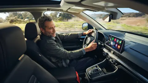 Modell som sitter i CR-V-hybridbilen och använder Honda Sensing 360.