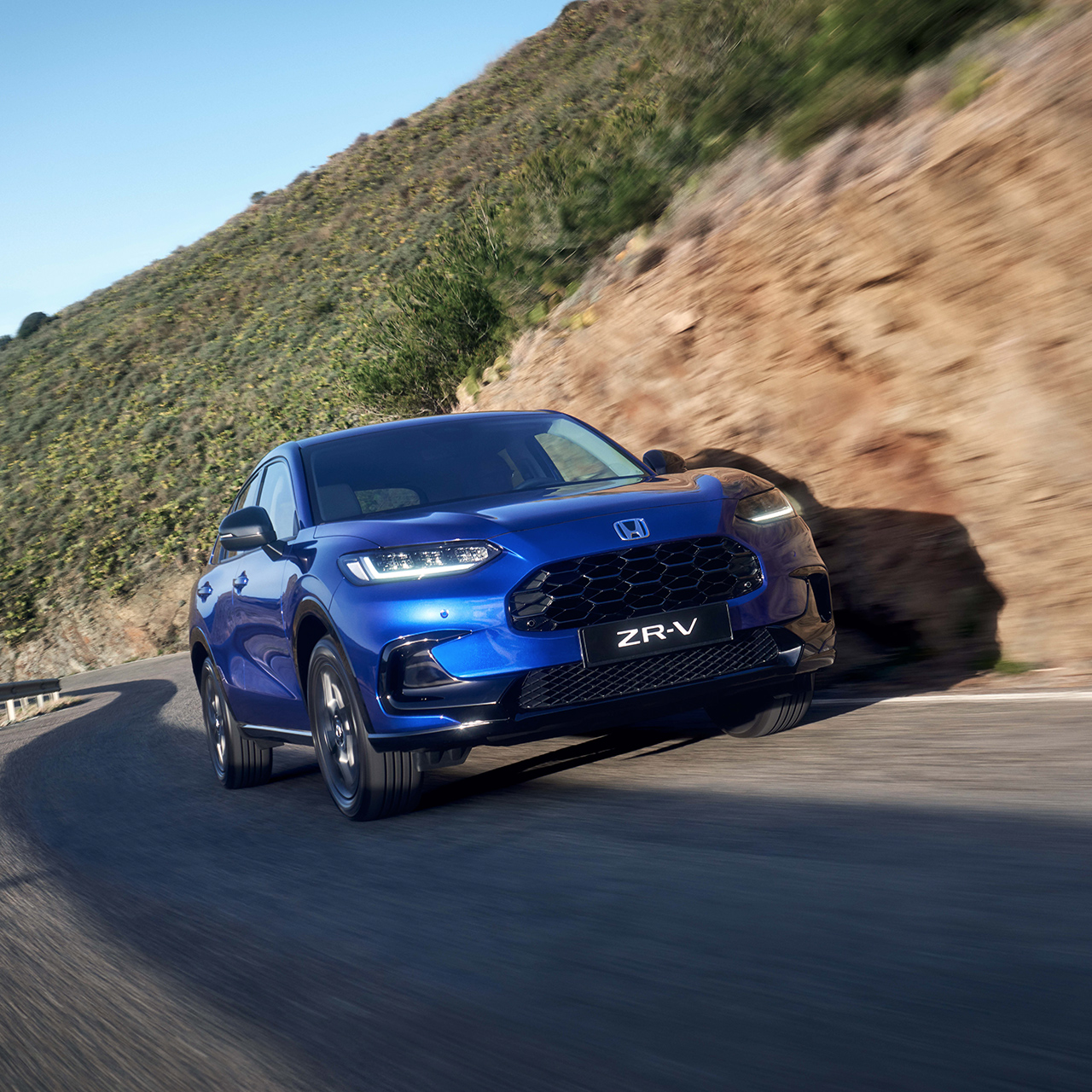 ZR-V-hybridbil som kör på en väg i bergsmiljö.