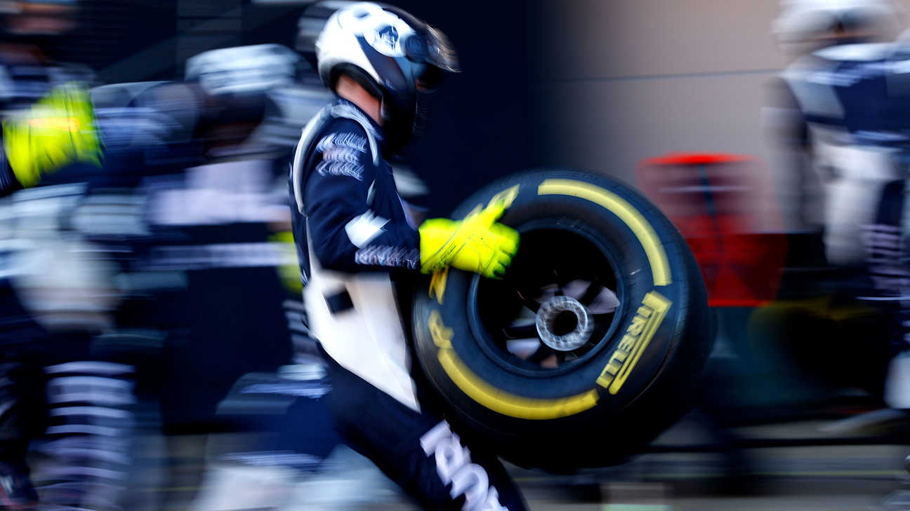 Scuderia AlphaTauri-mekaniker som håller ett däck i depån