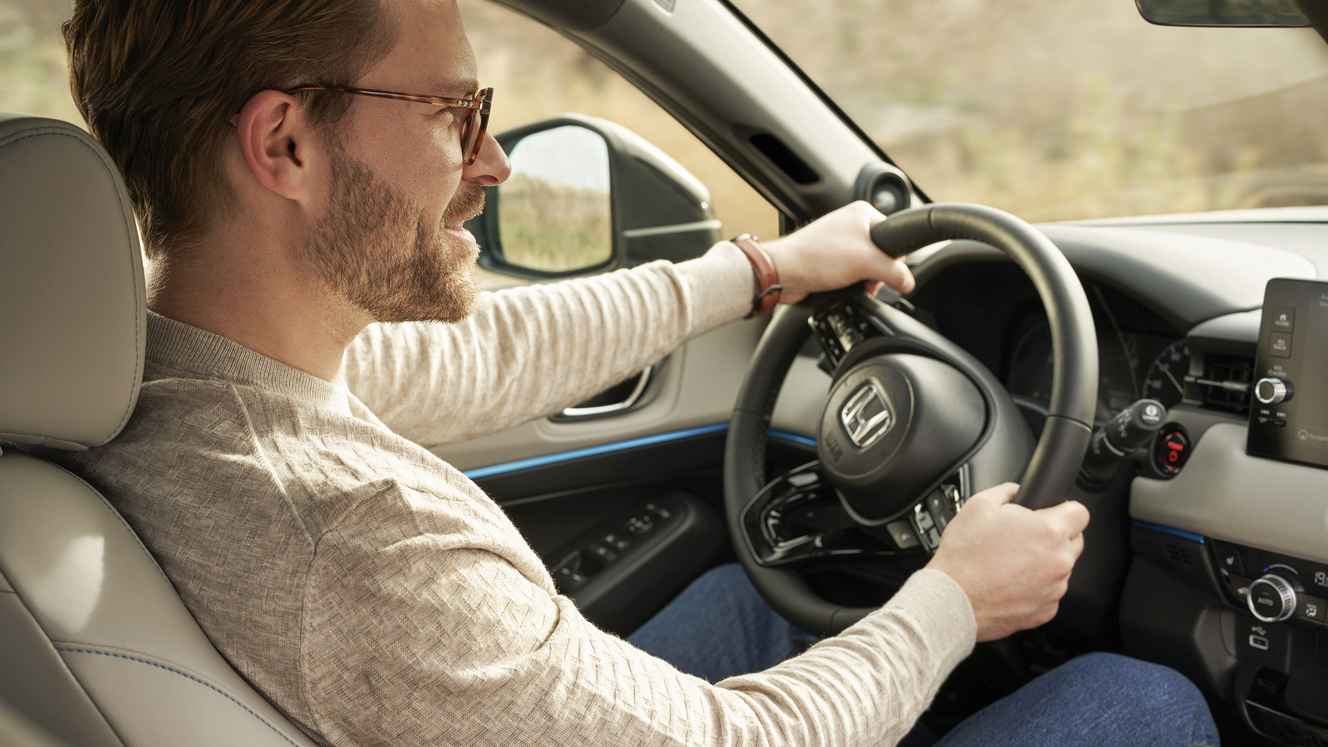 En man sitter på förarsätet i en Honda med händerna på ratten