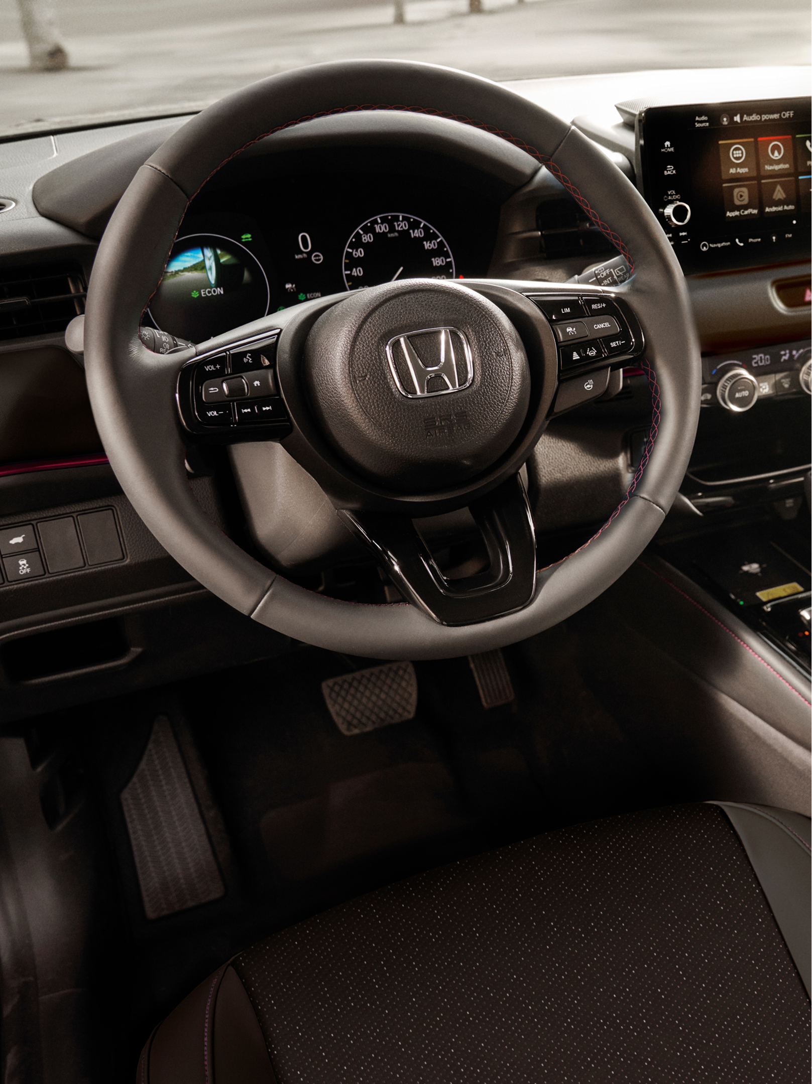 Interiörvy av en Honda HR-V som visar ratten, det digitala instrumentklustret, den centrala pekskärmen och den automatiska växelväljaren.
