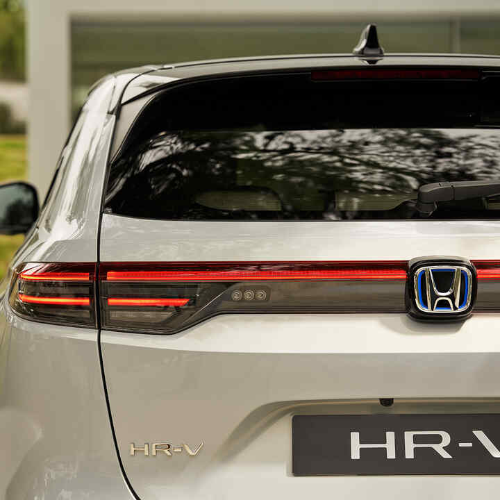 Par som passerar bredvid HR-V parkerad utanför en byggnad. 