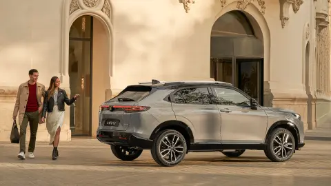 Honda HR-V sedd från sidan och parkerad utanför ett hotell, med ett par som passerar. 