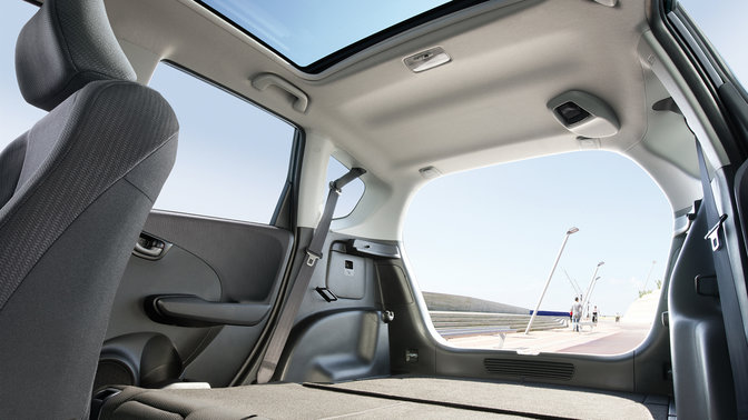 Trekvartsvy framifr&aring;n av Honda Jazz p&aring; en bl&aring;sig bergsv&auml;g.