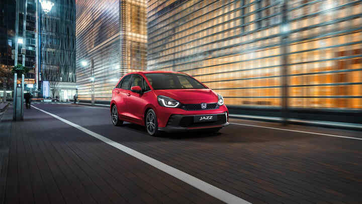3/4 vy framifrån av Honda Jazz framför en stadsbakgrund.