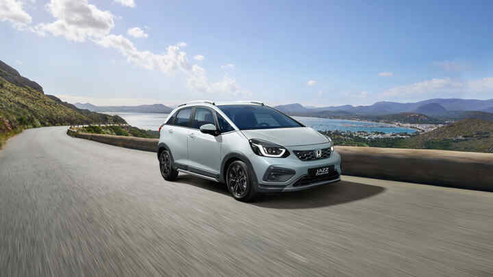 3/4 vy framifrån av Honda Jazz Hybrid med en naturskön utsikt i bakgrunden.