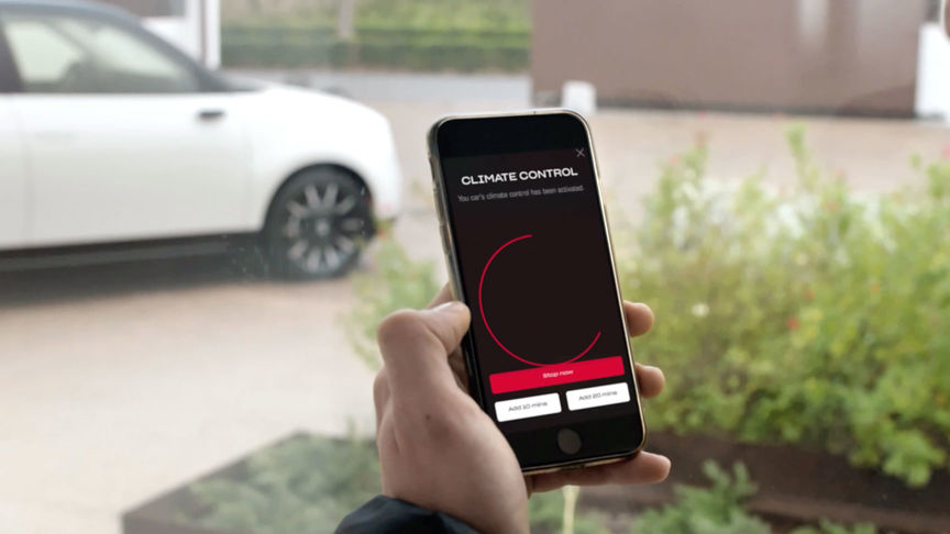 Man som tittar på My Honda Plus-appen med Honda Jazz Hybrid Crosstar i bakgrunden. 