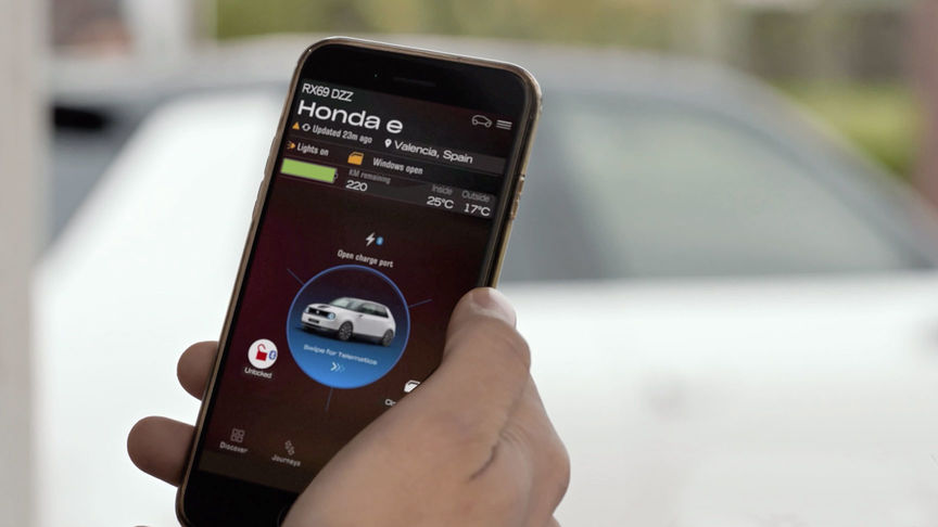 Man som tittar på My Honda Plus-appen med Honda Jazz Hybrid Crosstar i bakgrunden. 