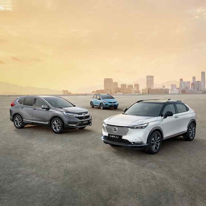 Ett antal Honda-hybridbilar parkerade framför ett stadslandskap