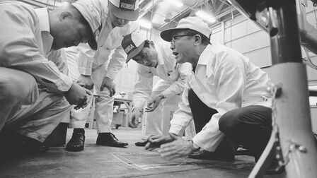 Soichiro Honda och några fabriksarbetare i vita overaller.