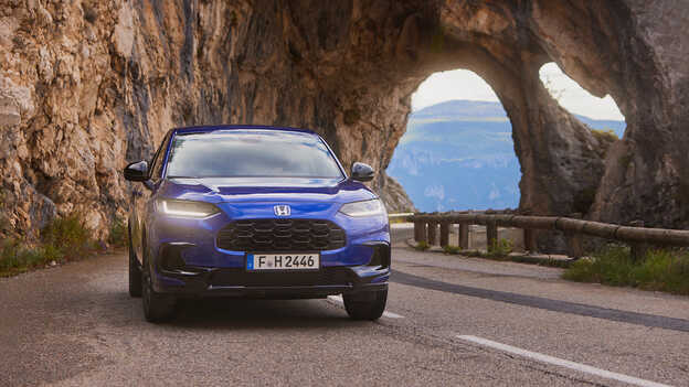 ZR-V Hybrid SUV blå med sportig drivlina kör på en bergsväg.