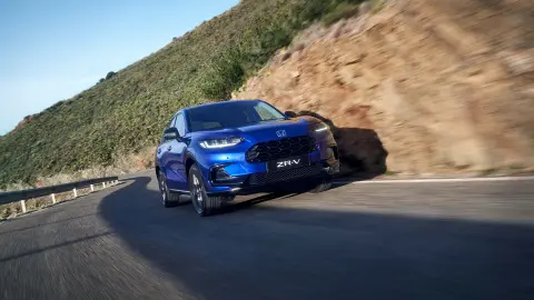 Honda ZR-V Hybrid Suv som kör på en väg i bergsmiljö.