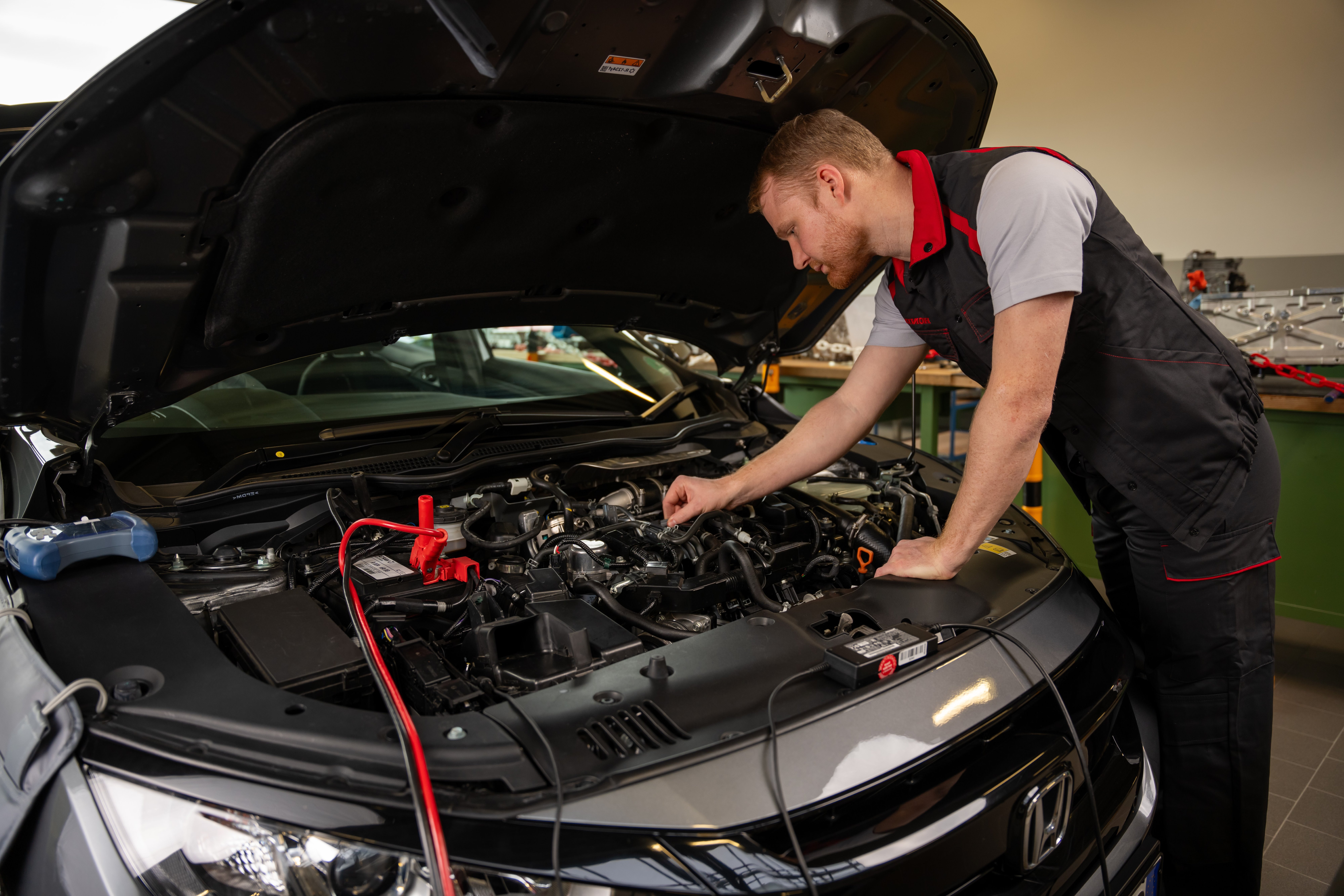En Honda-tekniker kontrollerar motorn i en Honda. 