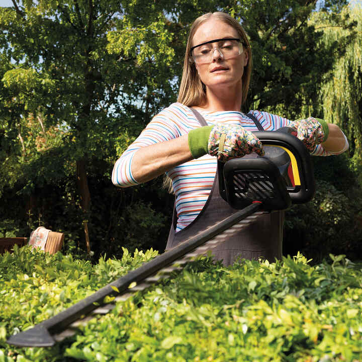 Kvinna som använder häcksax i trädgården