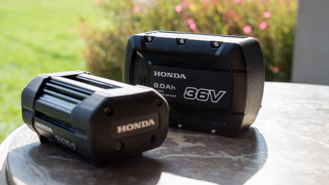 Närbild på batterier till Hondas batteridrivna utrustning i en trädgård.