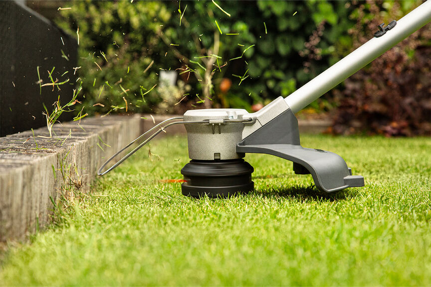 Batteridriven grästrimmer med högkvalitativ kaptråd på en gräsmatta.