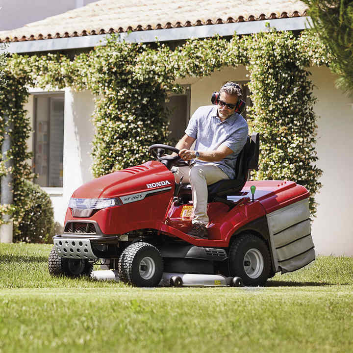 Man på åkgräsklippare i trädgården
