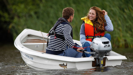 Ett leende par i en båt på en sjö.