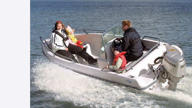 Båt med BF30-motor, körd av modeller, kustmiljö.