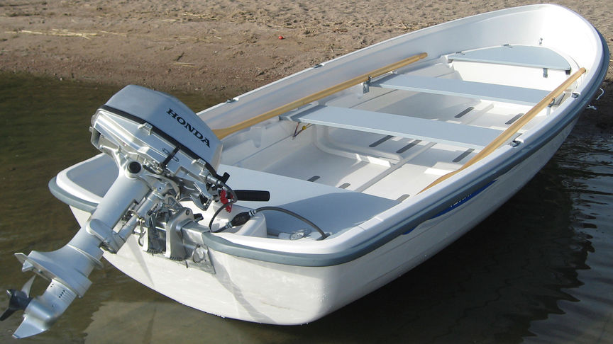 En båt på en strand med en Honda-motor monterad.