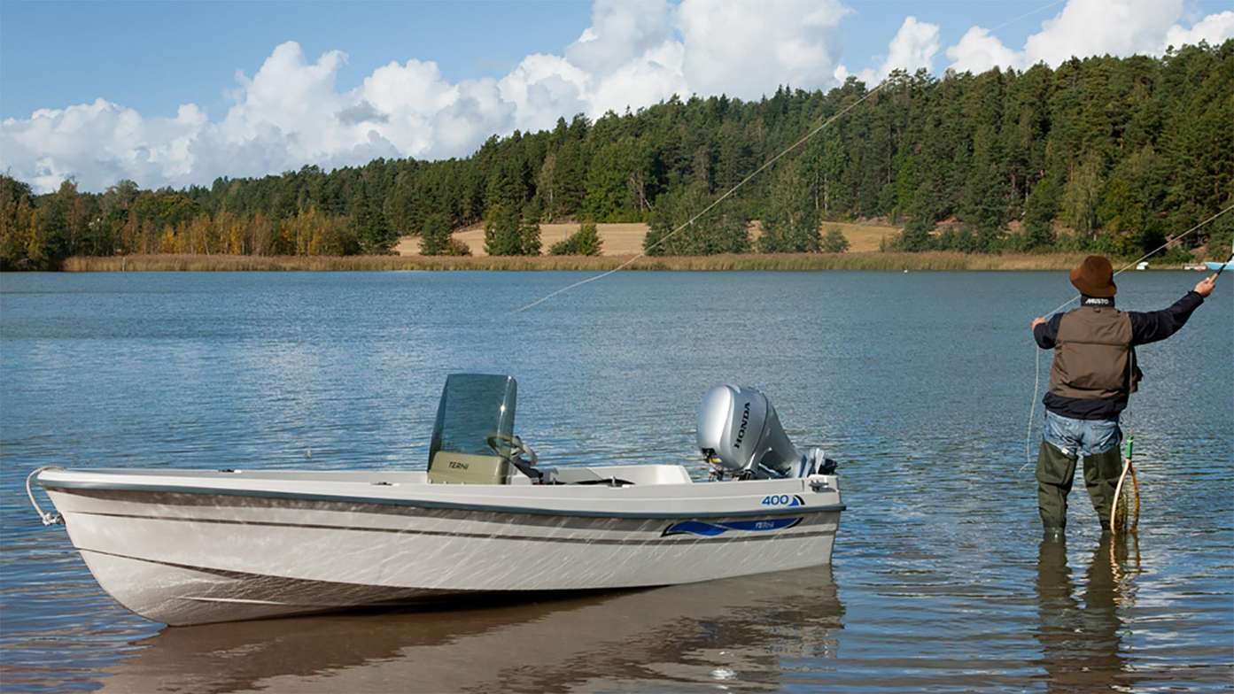 Man fiskar bredvid en liten båt med en utombordsmotor från Honda