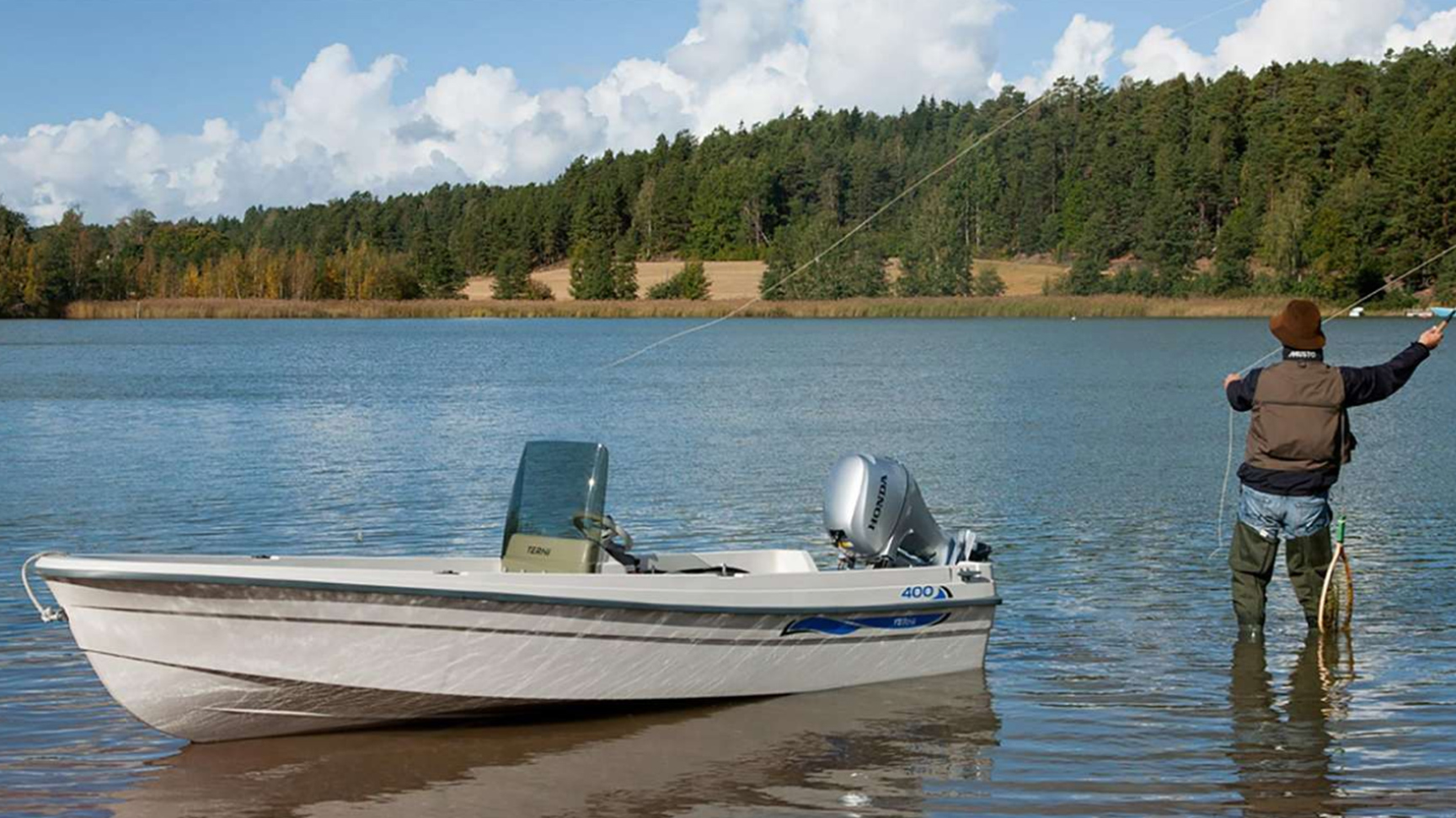 Modell som fiskar på sjön, med båt i närheten som visar upp BF8-10-motorn.