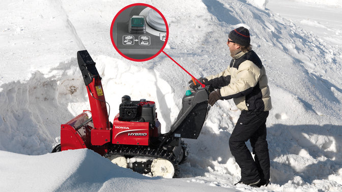 Hybridsnöslunga som körs av modell, fokus på återställningsknapp, i snömiljö.